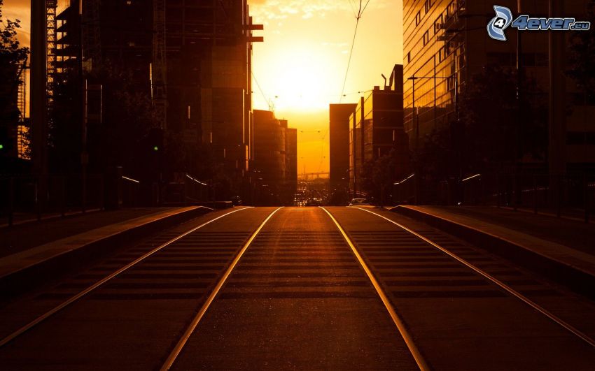 Straßenbahnschienen, Straße, Sonnenuntergang in der Stadt