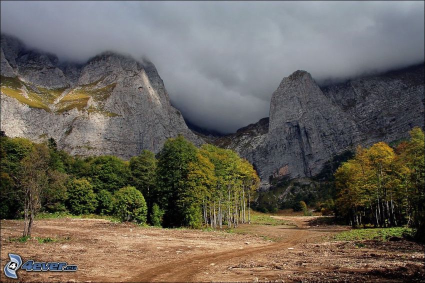 felsige Berge, Laubbäume, Wolken