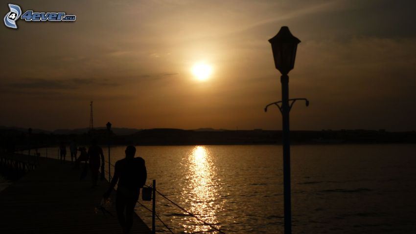 Sonnenuntergang über dem See, Ufer, Lampe, Silhouetten von Menschen