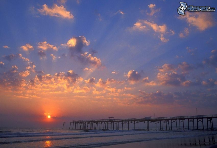 Sonnenuntergang über dem Meer, langer Pier, Wellen, Wolken