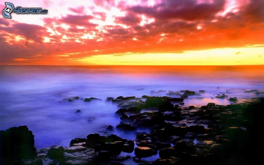 Strand beim Sonnenuntergang, felsige Küste, Meer, orange Himmel