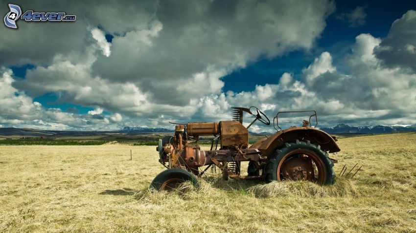gammal övergiven traktor, vrak, traktor på fält, moln