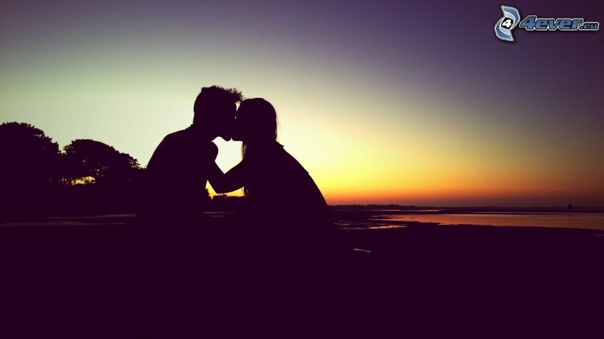 silhuett av ett par, puss, efter solnedgången