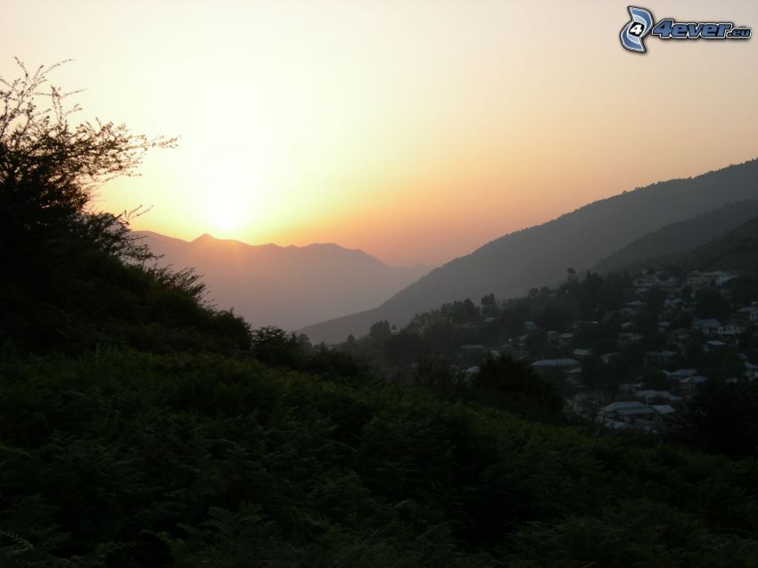 solnedgång bakom bergen, by