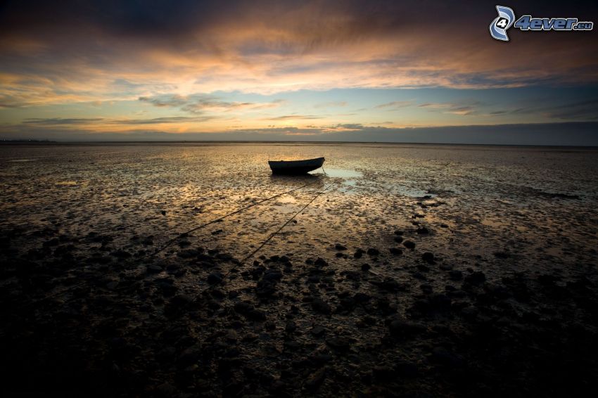övergiven båt, kust vid solnedgång
