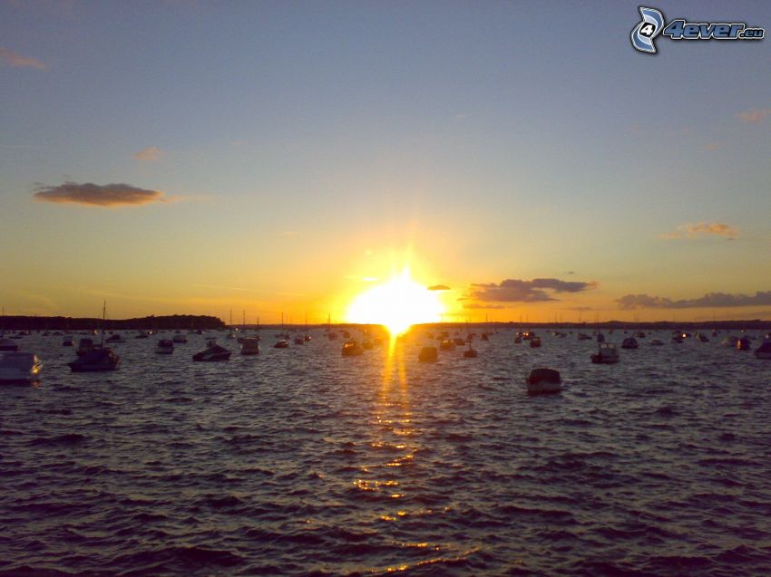 solnedgång över hav, båtar, vatten