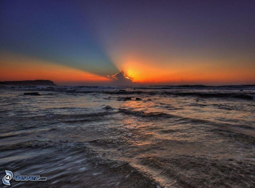 solnedgång över hav, solstrålar bakom moln