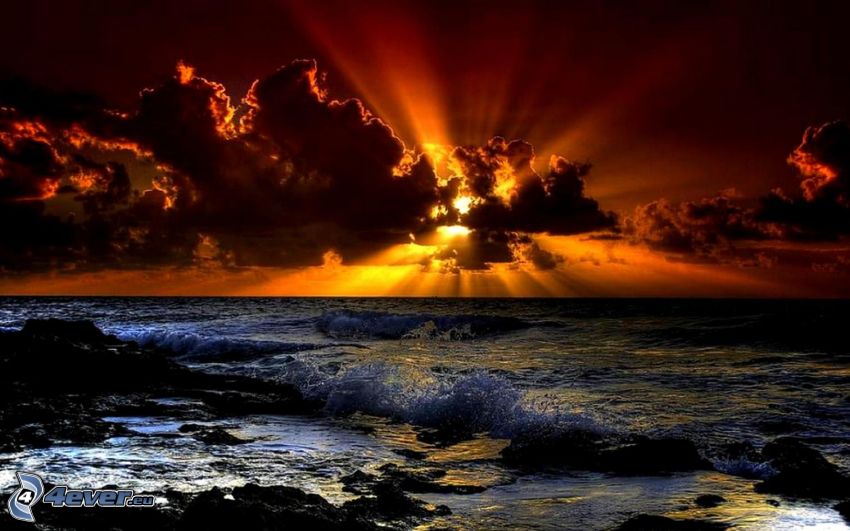 solnedgång över havet, sol bakom molnen