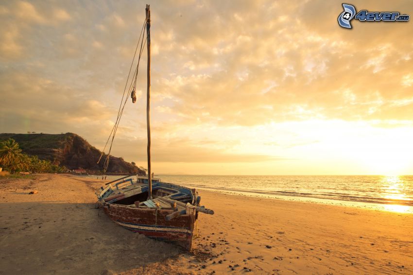 gammal båt på stranden, solnedgång