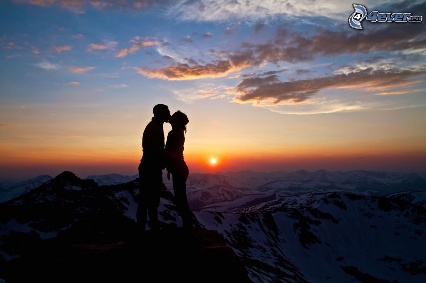 silueta de una pareja, puesta de sol sobre las montañas, beso