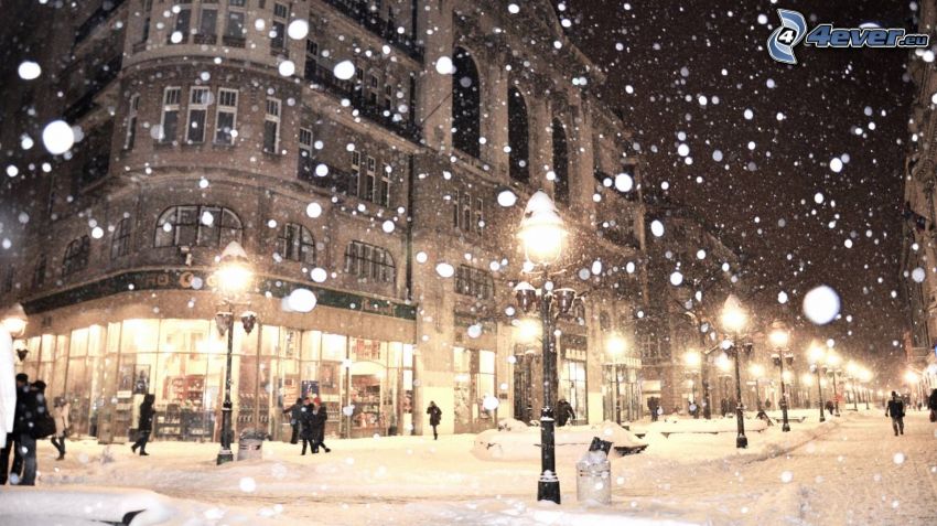 Ciudad al atardecer, calle cubierta de nieve, alumbrado público, la nevada
