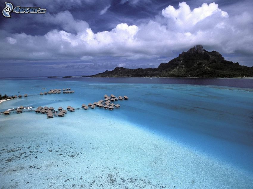 bungalows junto al mar en Bora Bora, isla rocosa, nubes