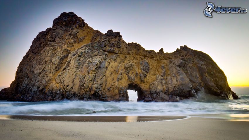 puerta rocosa en el mar, playa de arena
