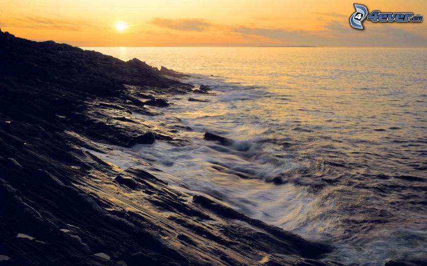 puesta de sol en el mar, costa de piedra