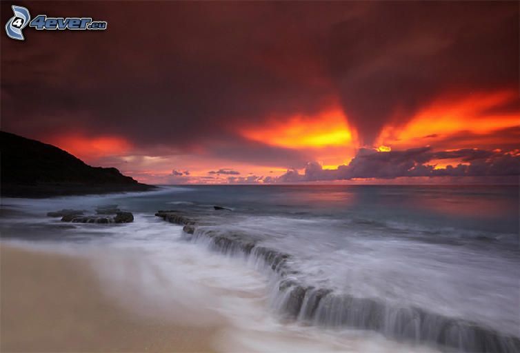 puesta de sol naranja sobre el mar, nubes, playa de arena