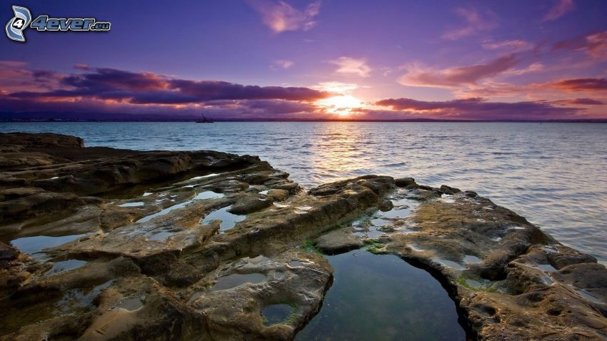 puesta de sol sobre el mar, costa de piedra
