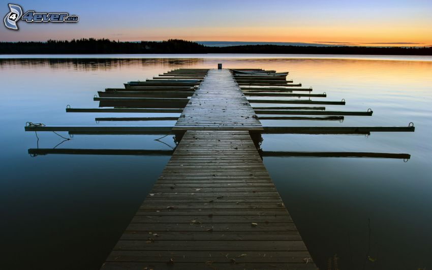 muelle de madera, puesta de sol sobre un lago