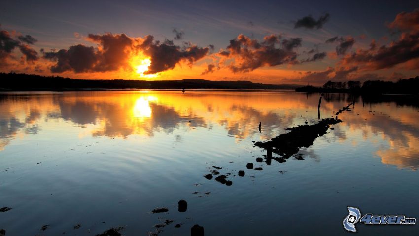 puesta de sol sobre el lago, atardecer, el sol detrás de los nubes, reflejo