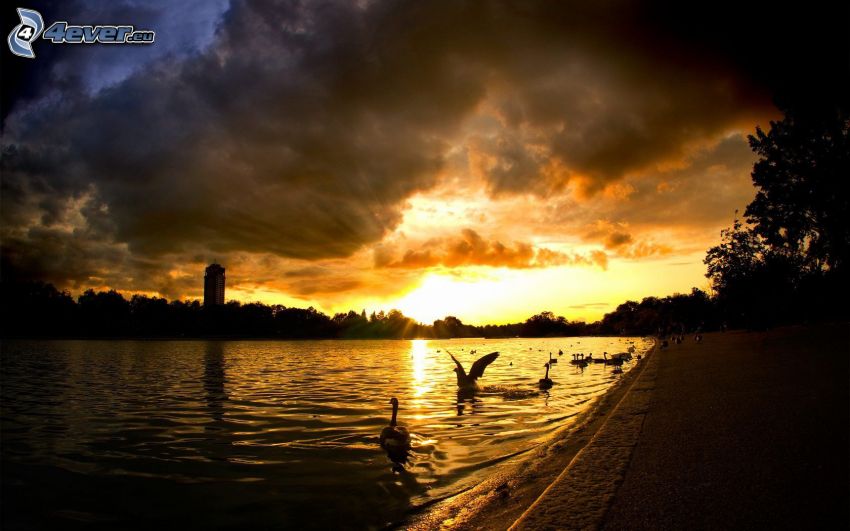 puesta de sol sobre un lago, nubes oscuras