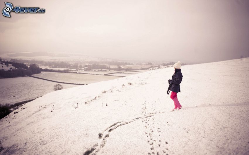 Chica en nieve, vista del paisaje, huellas en la nieve