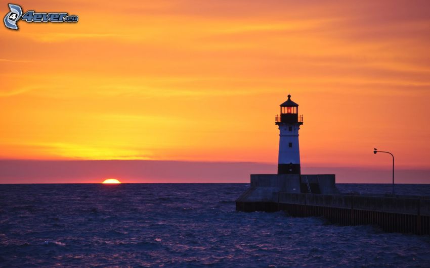Phare au coucher du soleil, jetée avec un phare, mer, ciel orange