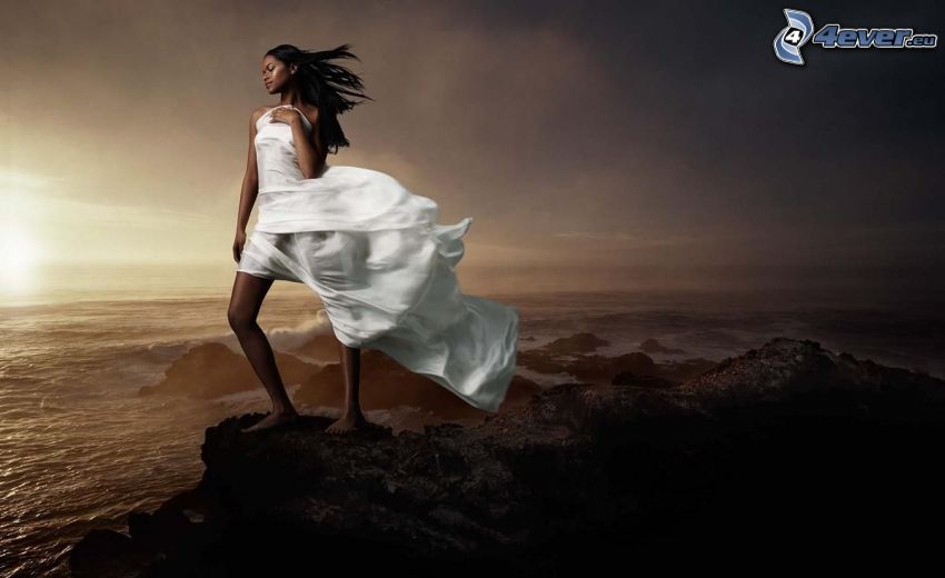 fille sur une falaise, femme noire, robe blanche, couchage de soleil à la mer, vue sur la mer