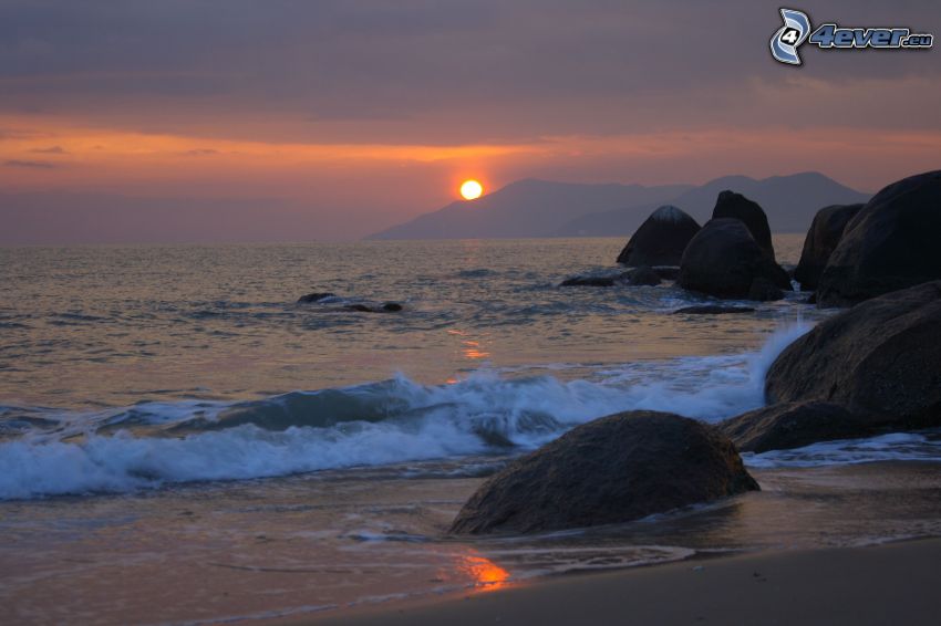 coucher du soleil derrière la colline, roches dans la mer, rochers