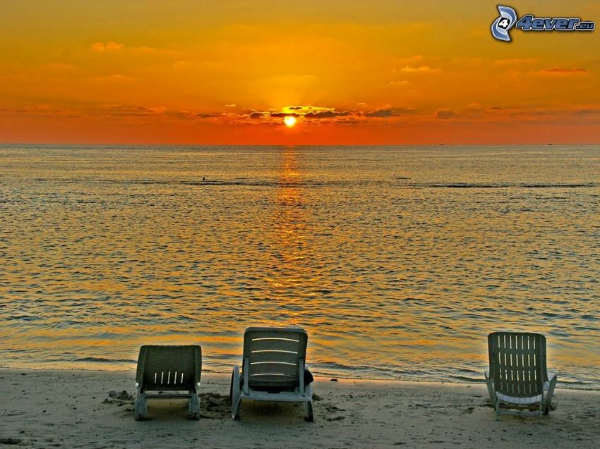 coucher du soleil orange sur la mer, chaises longues sur la plage