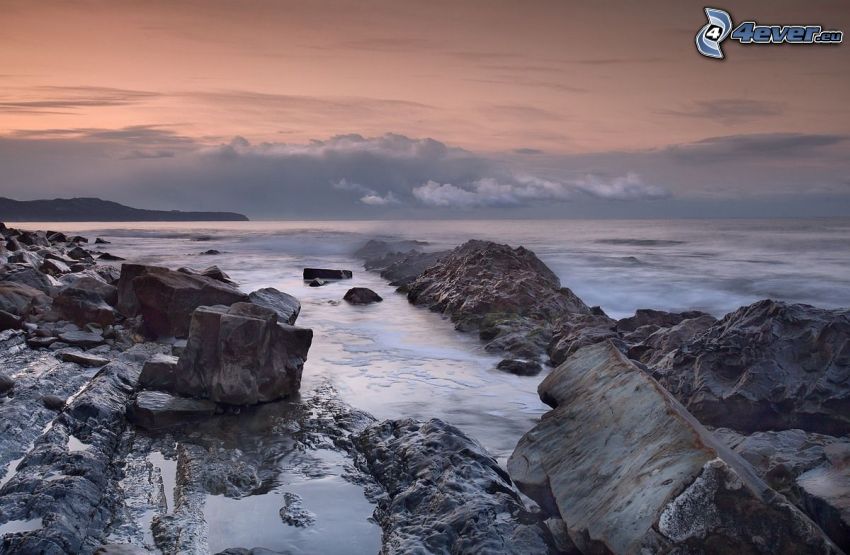 roches dans la mer, après le coucher du soleil, ciel orange