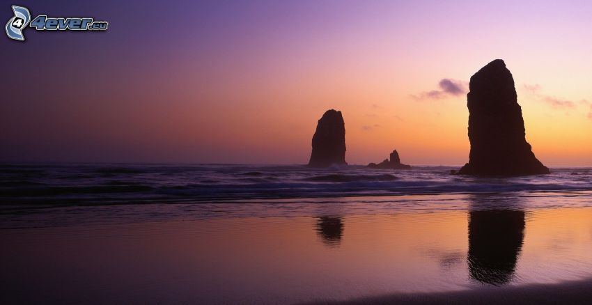 roches dans la mer, après le coucher du soleil