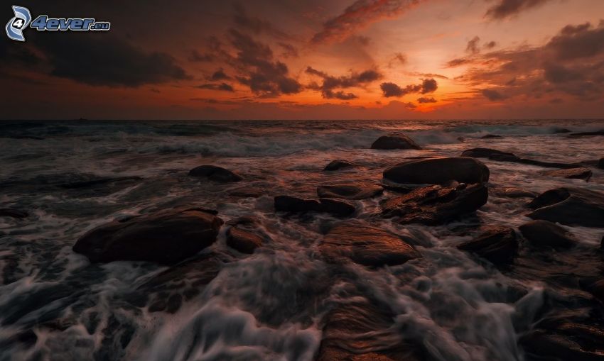 roches dans la mer, coucher du soleil orange sur la mer, après le coucher du soleil