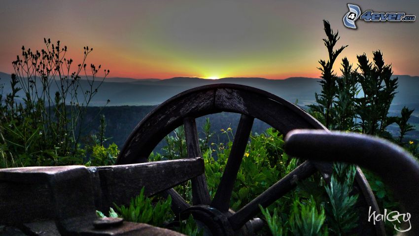 chariot en bois ancien, coucher du soleil derrière les montagnes, vert