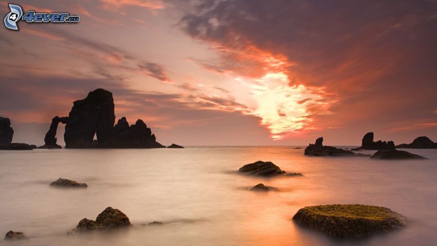 roches dans la mer, après le coucher du soleil