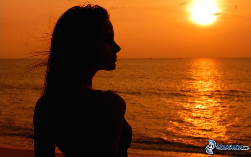 siluetta di donna al tramonto, tramonto sul mare, cielo arancione