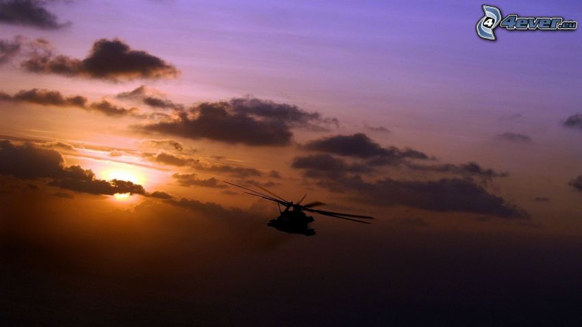 helikopter sziluettje, naplemente a felhők között