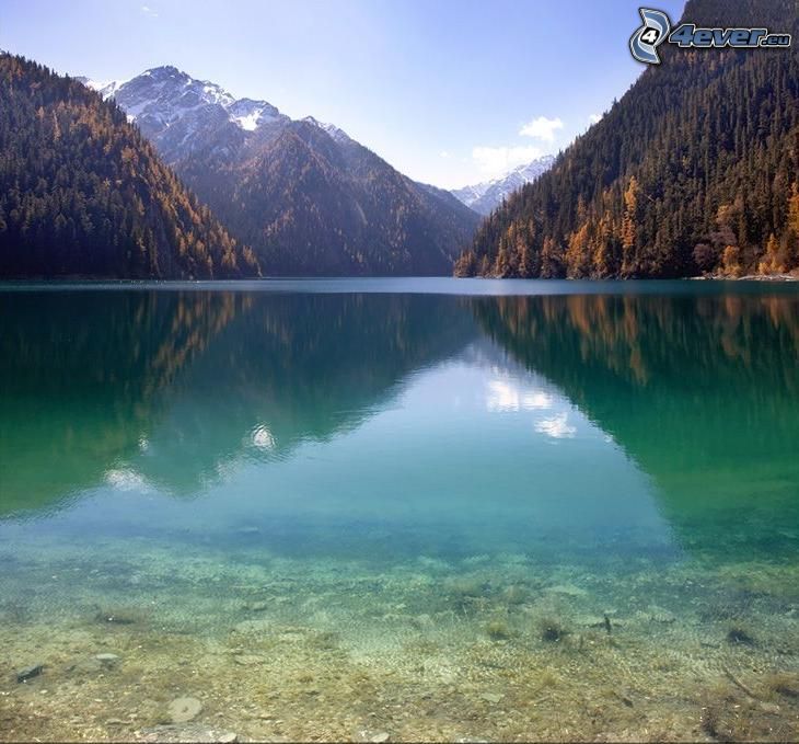 azúrkék tó, hófödte hegység a tó felett, tűlevelű erdő, sárga fák