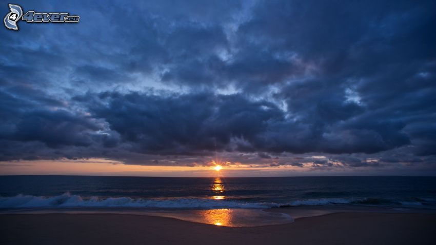 naplemente a tengeren, sötét égbolt, homokos tengerpart