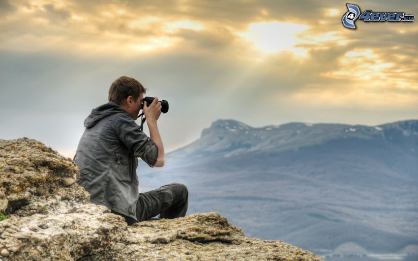 chłopak z aparatem fotograficznym, góry, promienie słoneczne
