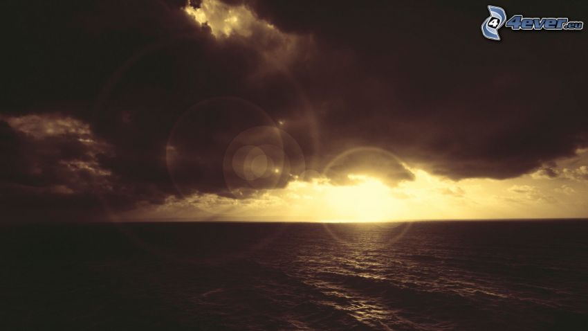 Zachód słońca nad morzem, ciemne chmury