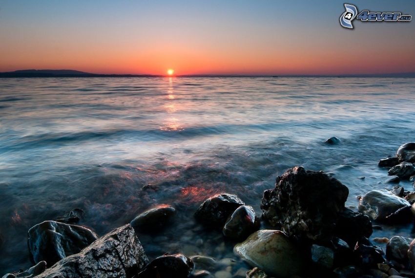 Zachód słońca nad morzem, kamienista plaża