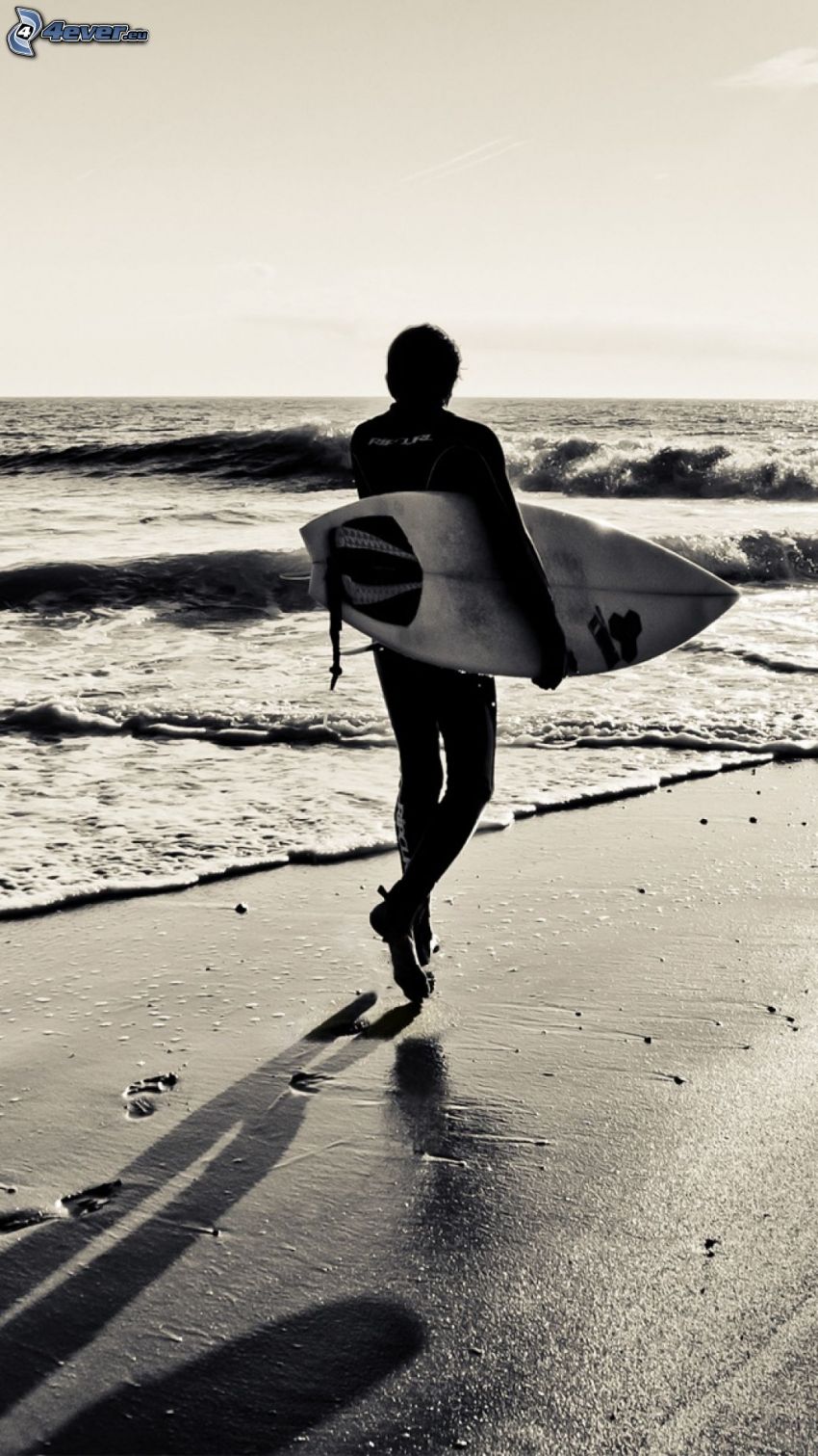 surfer, plaża piaszczysta, morze otwarte, ślady stóp na piasku, czarno-białe zdjęcie