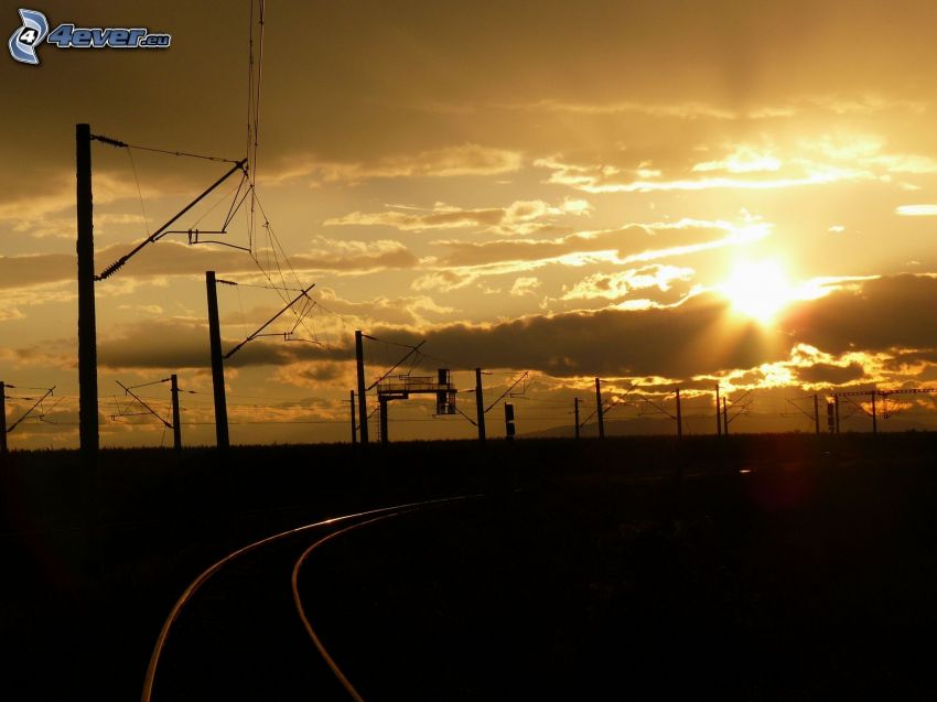 železnica, koľajnice, západ slnka v oblakoch