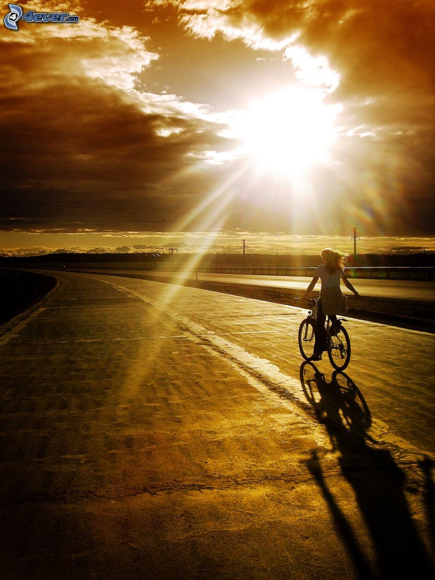 dievča na bicykli, západ slnka nad cestou