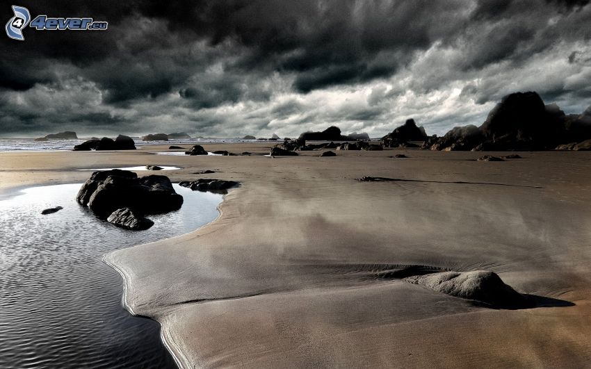 piesočná pláž, skaly, tmavé oblaky