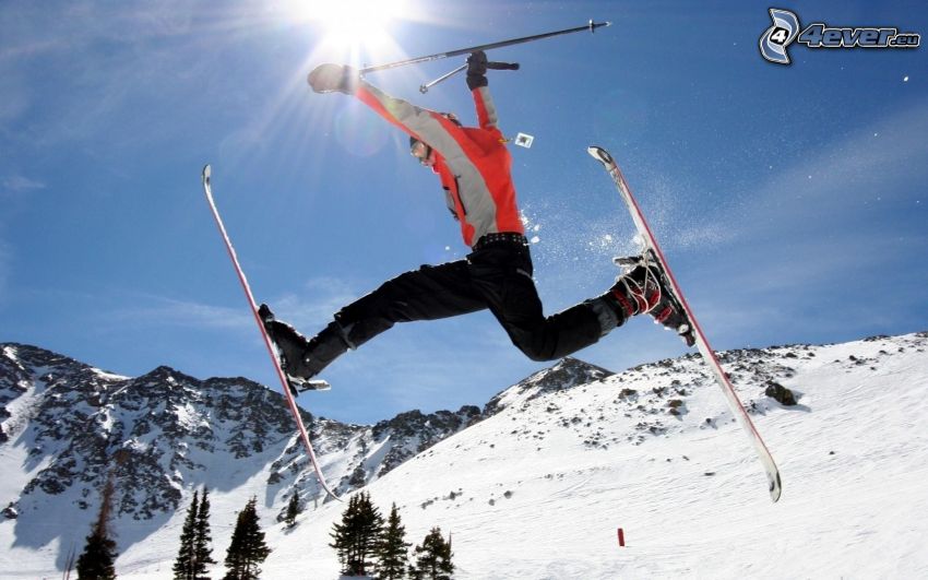 skok na lyžiach, lyžiar, zasnežené kopce, ihličnaté stromy, modrá obloha, slnko, akrobacia