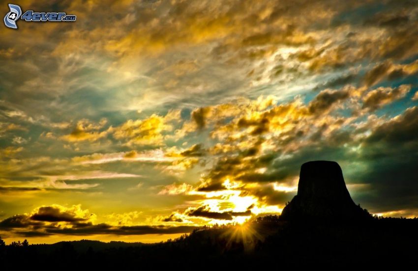 Devils Tower, rock, silhouette, sunset, sunbeams, yellow clouds