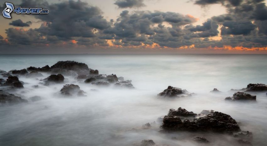 rocks in the sea, after sunset, clouds