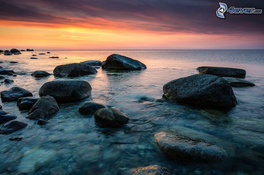 rocks in the sea, after sunset, orange sky