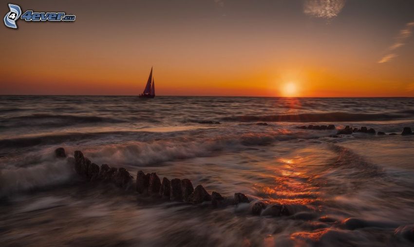 sunset behind the sea, sailing boat, rocks in the sea