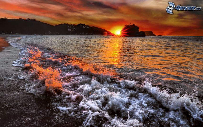 sunset behind the sea, waves on the shore